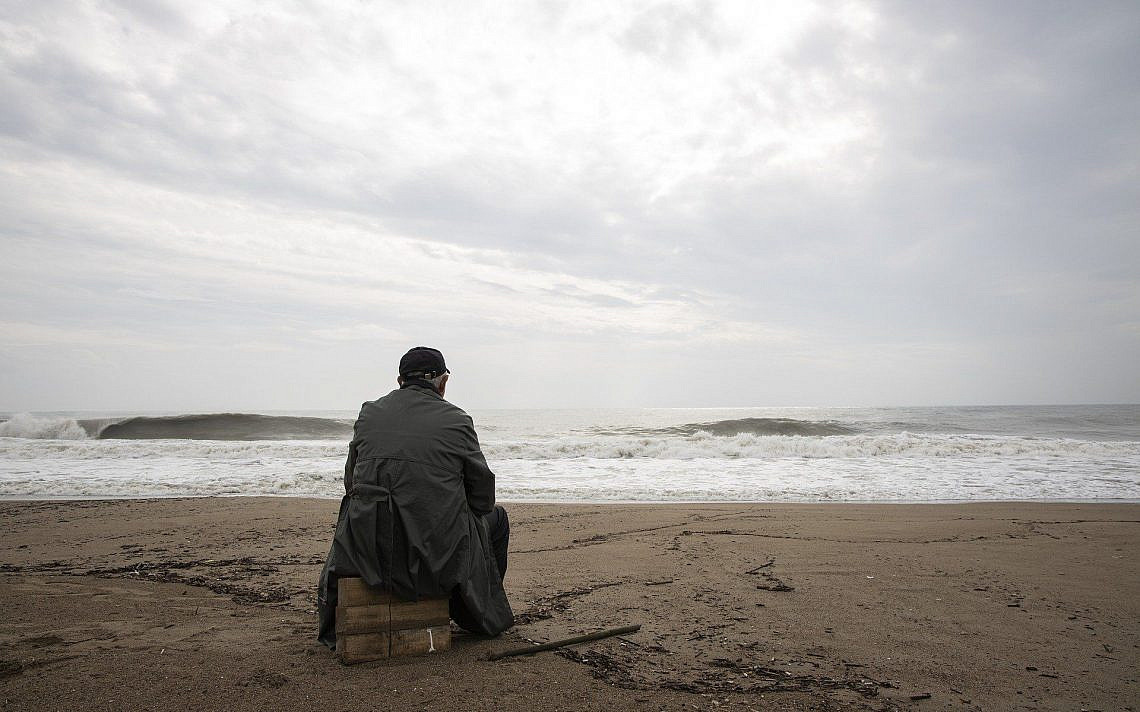 אדם בודד יושב אל מול חוף הים