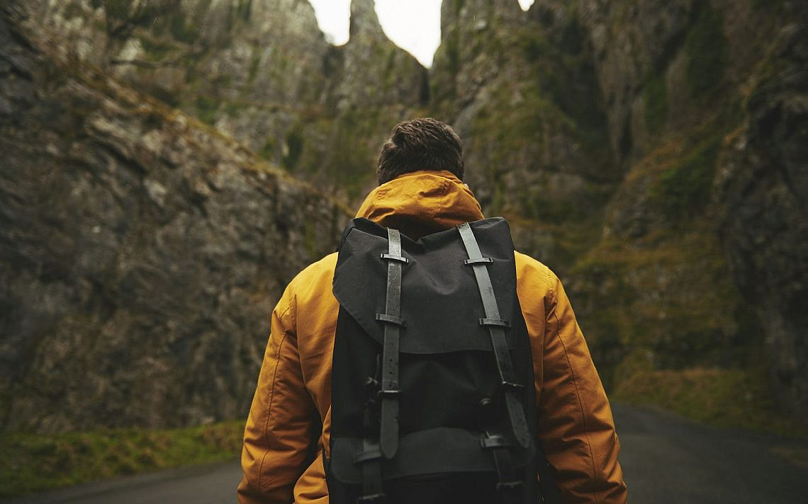 אדם במעיל צהוב נושא תרמיל מול ההרים, צילום: Pixabay
